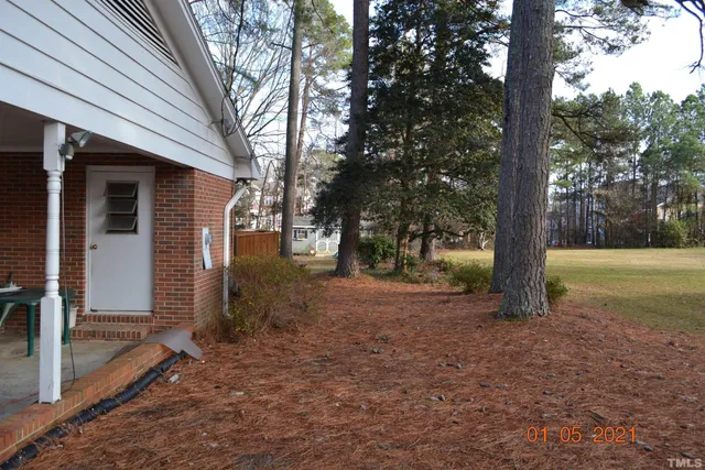 a view of a house with backyard and trees