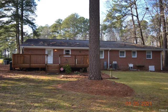 a view of a house with a yard and large tree