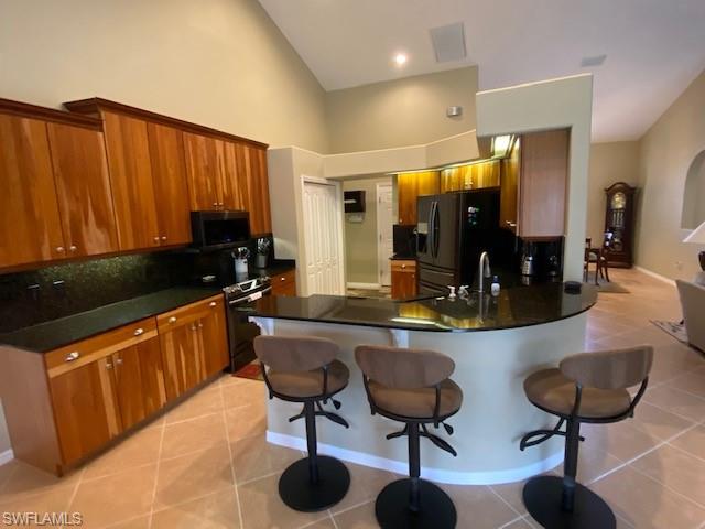 8886 Lely Island Circle Naples, FL 34113 - Photo 9 of 14 a kitchen with stainless steel appliances kitchen island granite countertop a table chairs in it and a wooden floors