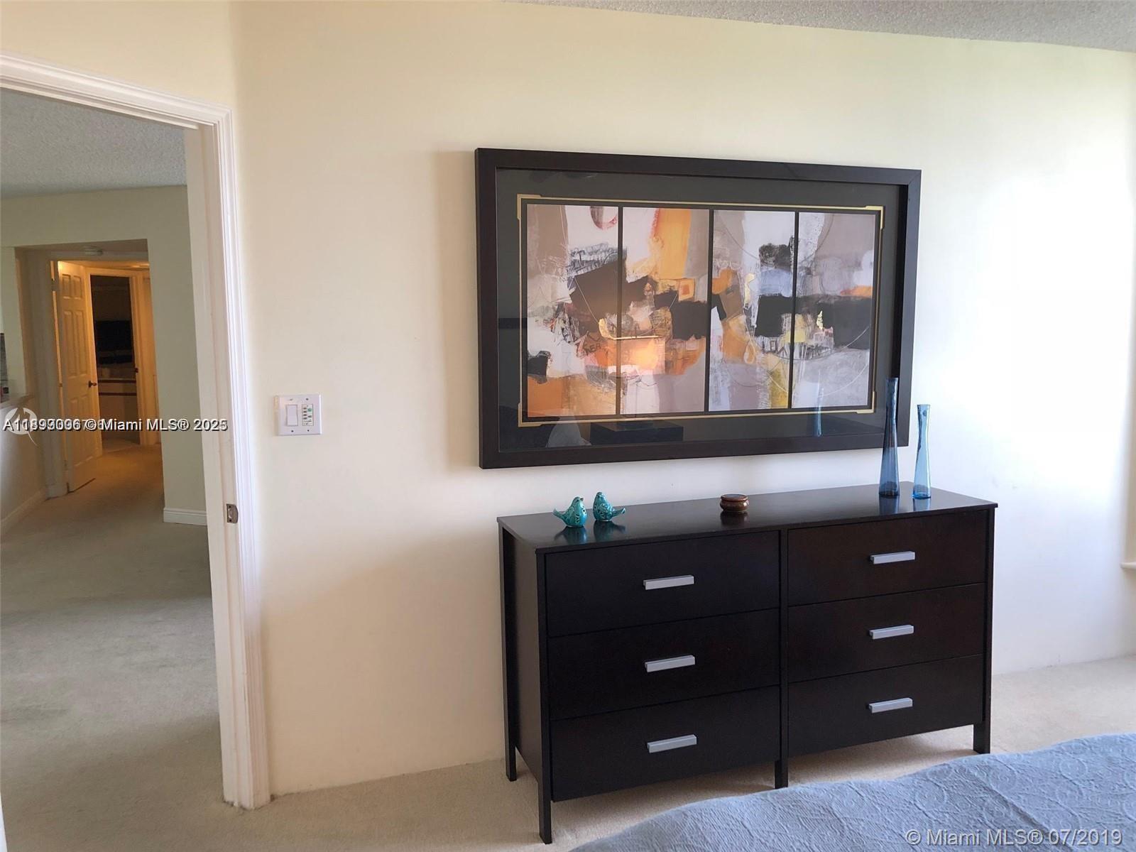 3530 Mystic Pointe Drive, Unit 1008 Aventura, FL 33180 - Photo 11 of 32 a room with a dresser and a window