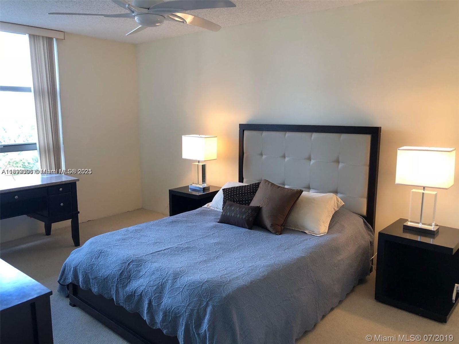 3530 Mystic Pointe Drive, Unit 1008 Aventura, FL 33180 - Photo 10 of 32 a bedroom with a bed and a lamp