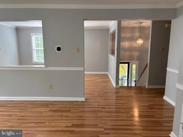 a view of an empty room with window and wooden floor