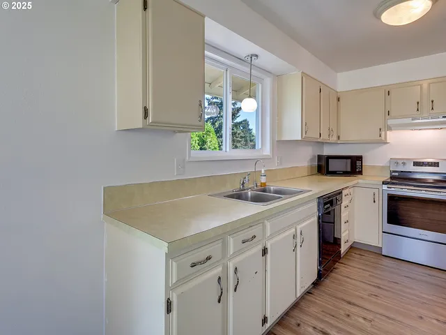 a kitchen with cabinets appliances a sink and a window