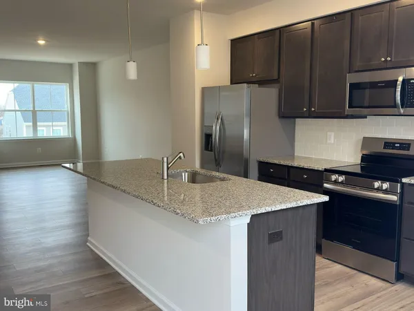 a kitchen with stainless steel appliances granite countertop a sink a microwave a refrigerator and a stove