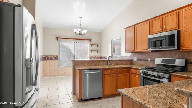 a kitchen with stainless steel appliances granite countertop a stove top oven a sink dishwasher a refrigerator and a fireplace with wooden floor