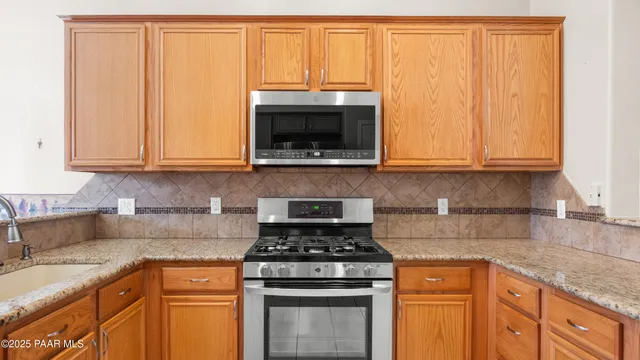 a kitchen with granite countertop white cabinets and stainless steel appliances