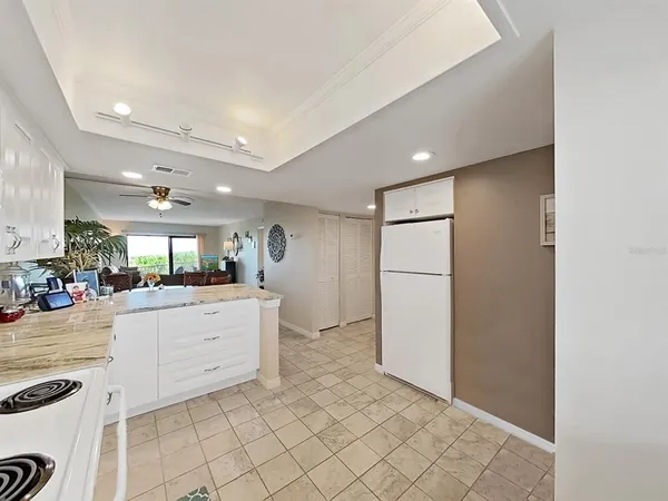 a large white kitchen with a sink and dishwasher a refrigerator with white cabinets