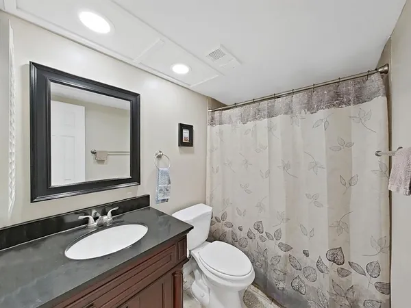 a bathroom with a granite countertop sink toilet a mirror a shower and a sink