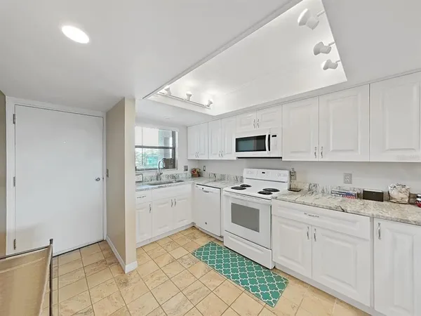 a kitchen with granite countertop white cabinets and white appliances