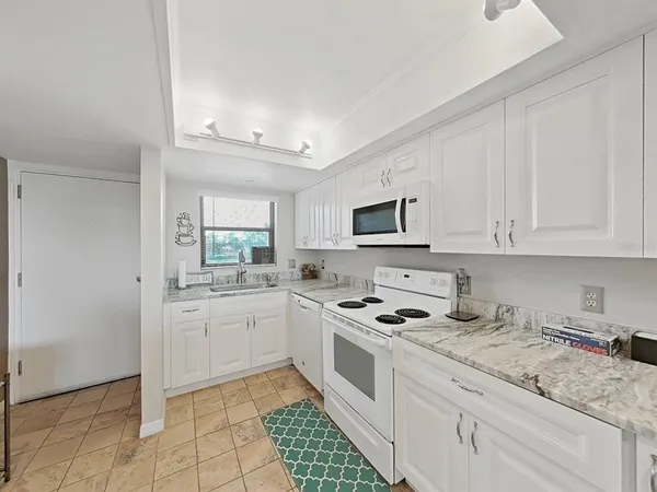 a kitchen with granite countertop white cabinets and white appliances