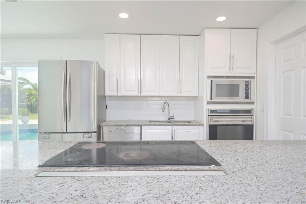 9104 Pineapple Road Fort Myers, FL 33967 - Photo 5 of 24 a kitchen with kitchen island granite countertop a stove a sink and a microwave