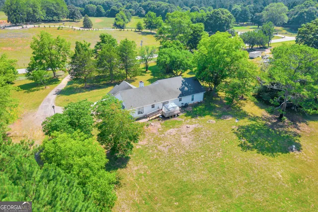 an aerial view of residential house with outdoor space and trees all around