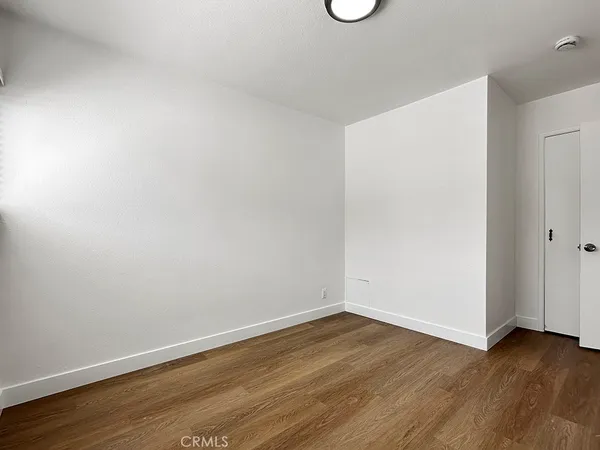 a view of an empty room with wooden floor and window