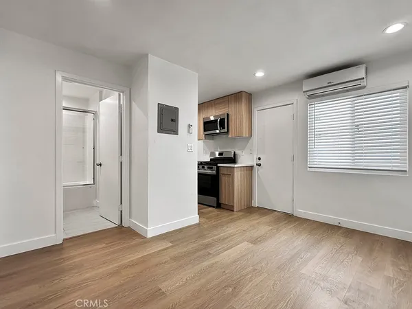 an empty room with wooden floor and a kitchen