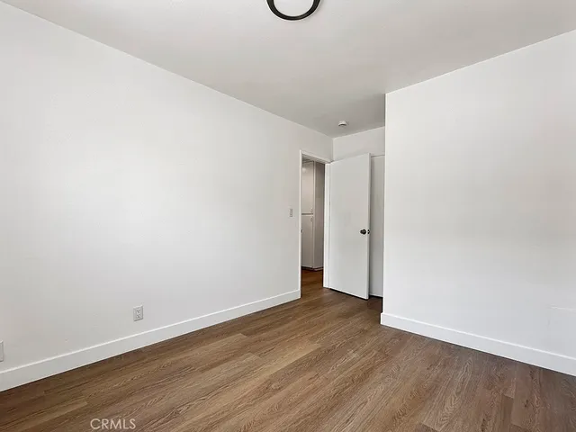 a view of an empty room with wooden floor and windows