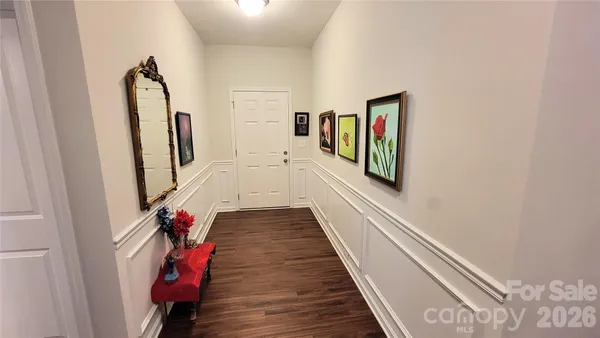a hallway with wooden floor chandelier and entryway