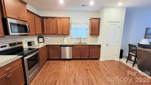 a kitchen with stainless steel appliances granite countertop a stove top oven a sink dishwasher and wooden floor