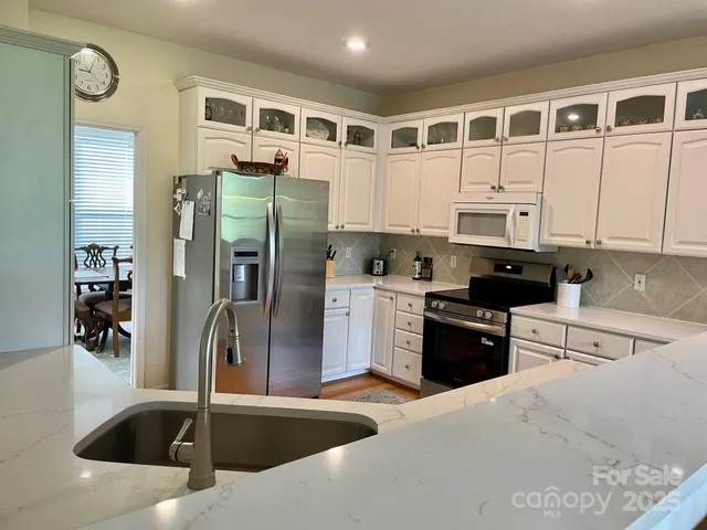 a kitchen with stainless steel appliances granite countertop a refrigerator a stove and a sink with wooden floor