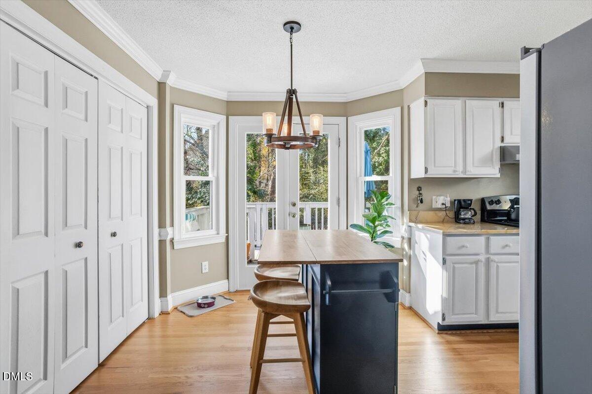 3516 East Jameson Road Raleigh, NC 27604 - Photo 8 of 32 a open kitchen with kitchen island granite countertop a stove a sink a refrigerator and white cabinets with wooden floor