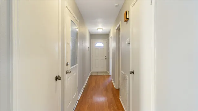 a view of a hallway with wooden floor and a bathroom