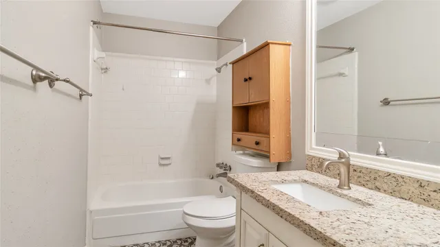 a bathroom with a granite countertop sink a toilet and shower