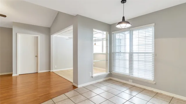 a view of an empty room with window chandelier fan and fire place