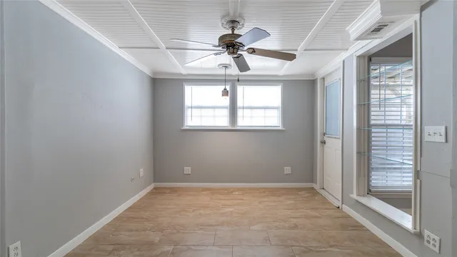 an empty room with a chandelier fan and windows