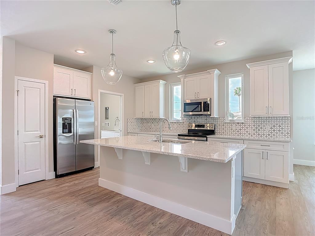 3487 Sheephead Drive Hernando Beach, FL 34607 - Photo 39 of 77 a large kitchen with stainless steel appliances kitchen island granite countertop a stove a sink a refrigerator and white cabinets with wooden floor