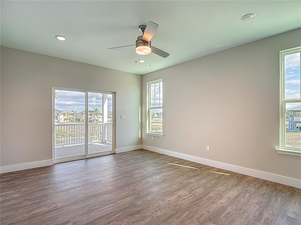3487 Sheephead Drive Hernando Beach, FL 34607 - Photo 52 of 77 an empty room with wooden floor chandelier fan and windows