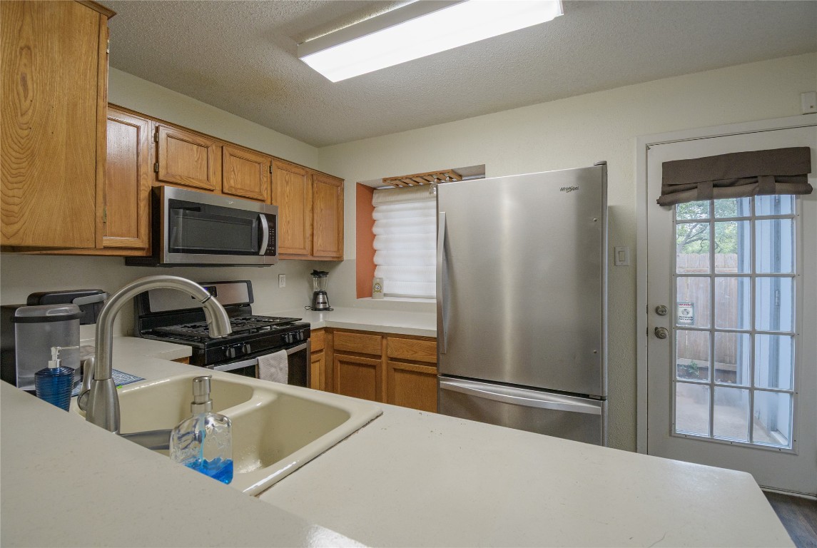 1411 Gracy Farms Lane, Unit 14 Austin, TX 78758 - Photo 5 of 16 a kitchen with stainless steel appliances a refrigerator a sink a stove a microwave and cabinets