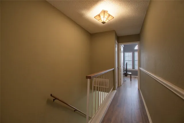 a view of a hallway with wooden floor and a chandelier