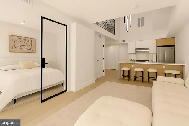 a living room with stainless steel appliances furniture and a kitchen view