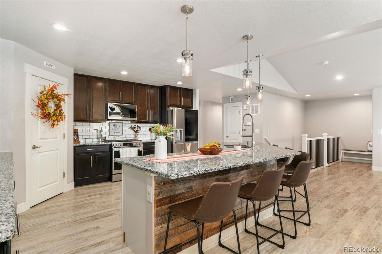 16477 Stoneleigh Road Platteville, CO 80651 - Photo 8 of 37 a kitchen with stainless steel appliances kitchen island granite countertop a stove top oven a refrigerator a sink and a dining table with wooden floor