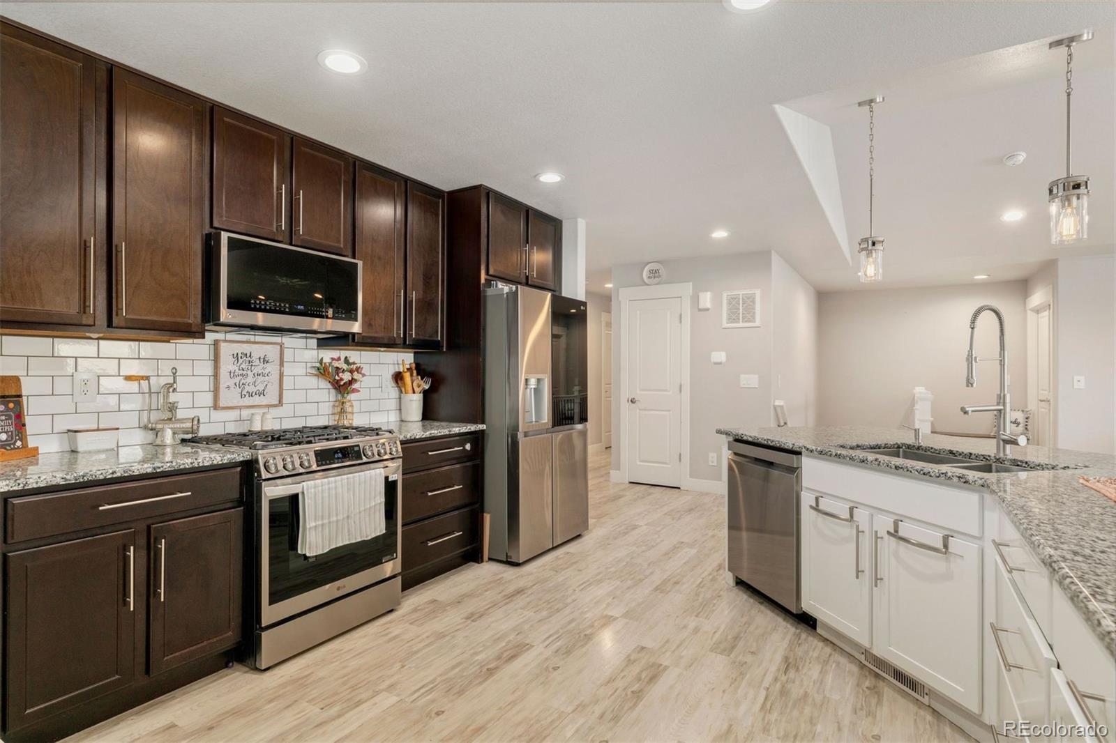 16477 Stoneleigh Road Platteville, CO 80651 - Photo 10 of 37 a kitchen with stainless steel appliances granite countertop a stove top oven a sink dishwasher a refrigerator and a oven with wooden floor