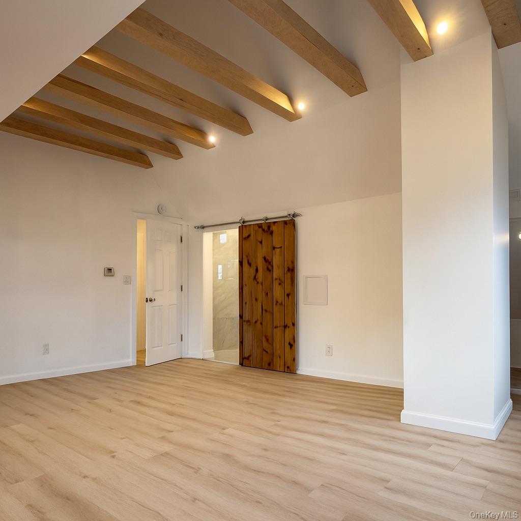 88 Cold Spring Road Liberty, NY 12754 - Photo 23 of 32 Primary bedroom featuring a barn door and light wood-type flooring and walk-in closet.