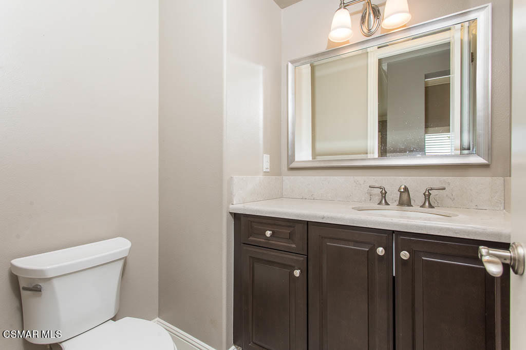 7342 Nicklaus Road Moorpark, CA 93021 - Photo 27 of 55 a bathroom with a granite countertop sink a toilet and a mirror