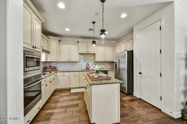 a kitchen with stainless steel appliances granite countertop a refrigerator a sink dishwasher a stove and white cabinets with wooden floor