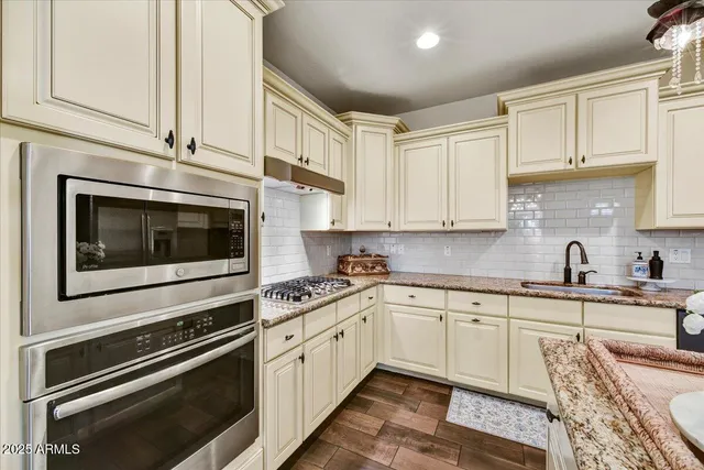 a kitchen with stainless steel appliances white cabinets and a stove top oven
