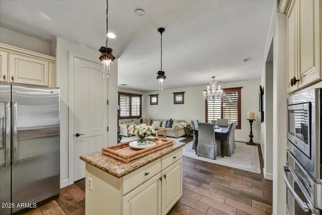 a kitchen with stainless steel appliances granite countertop a stove a refrigerator and a dining table with wooden floor