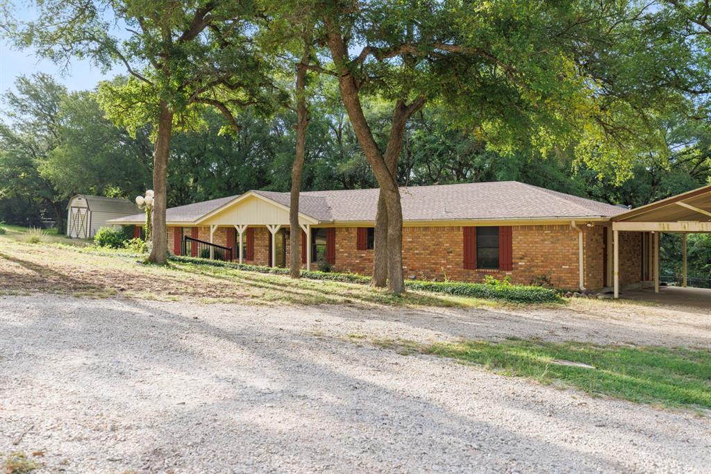 Single-story brick residence with an attached carport, covered front porch, and a gravel driveway
