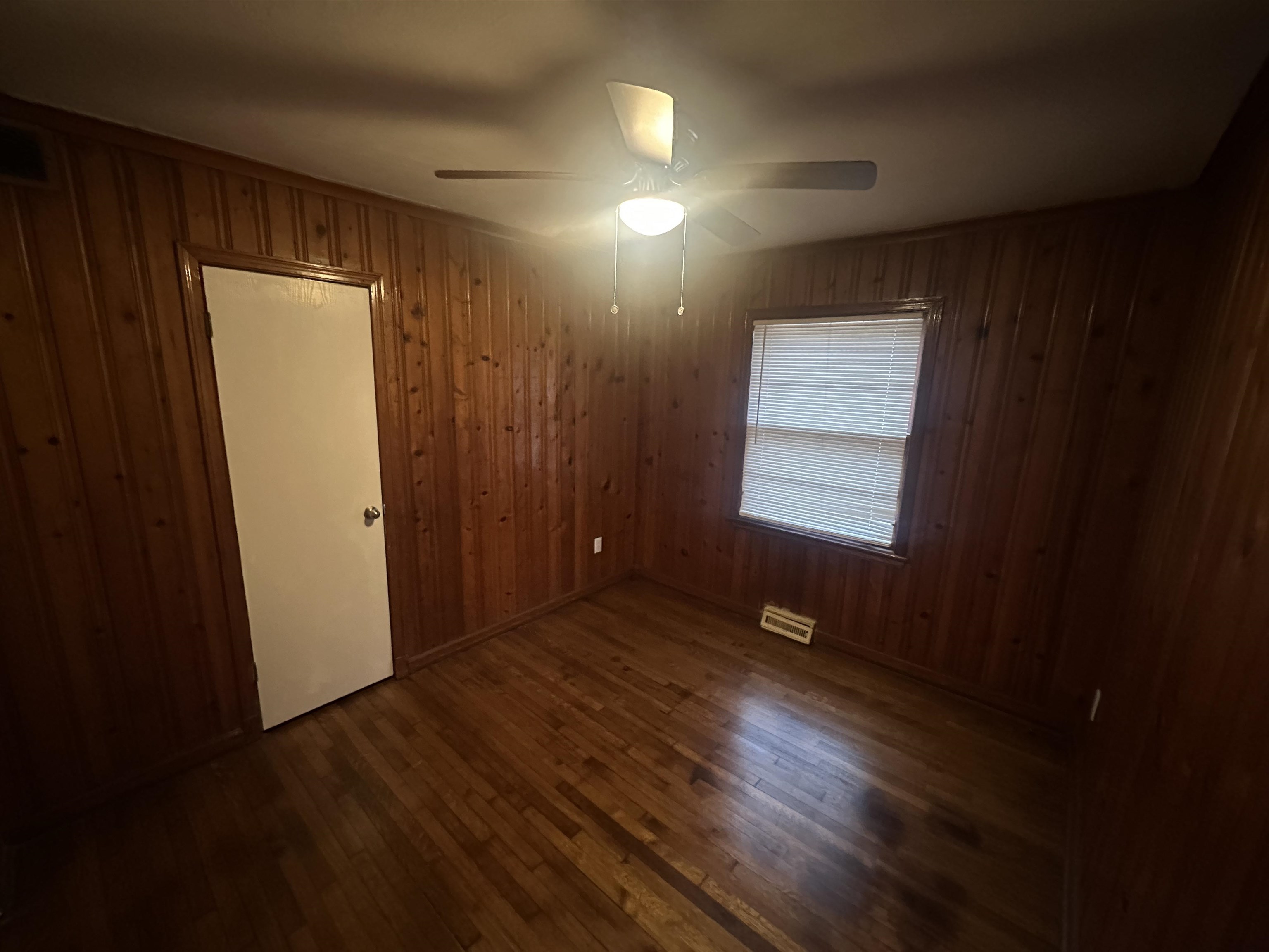 1285 Old Hickory Road Memphis, TN 38116 - Photo 15 of 31 Empty room featuring dark wood-style floors, wood walls, and a ceiling fan