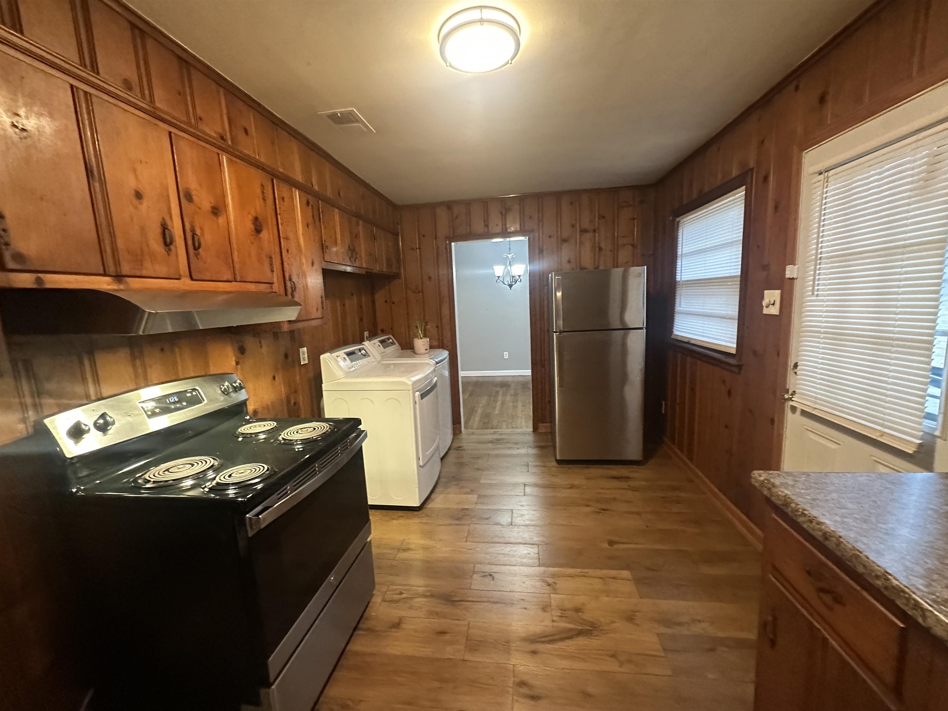 1285 Old Hickory Road Memphis, TN 38116 - Photo 6 of 31 Kitchen featuring light wood-style floors, appliances with stainless steel finishes, brown cabinets, independent washer and dryer, and under cabinet range hood