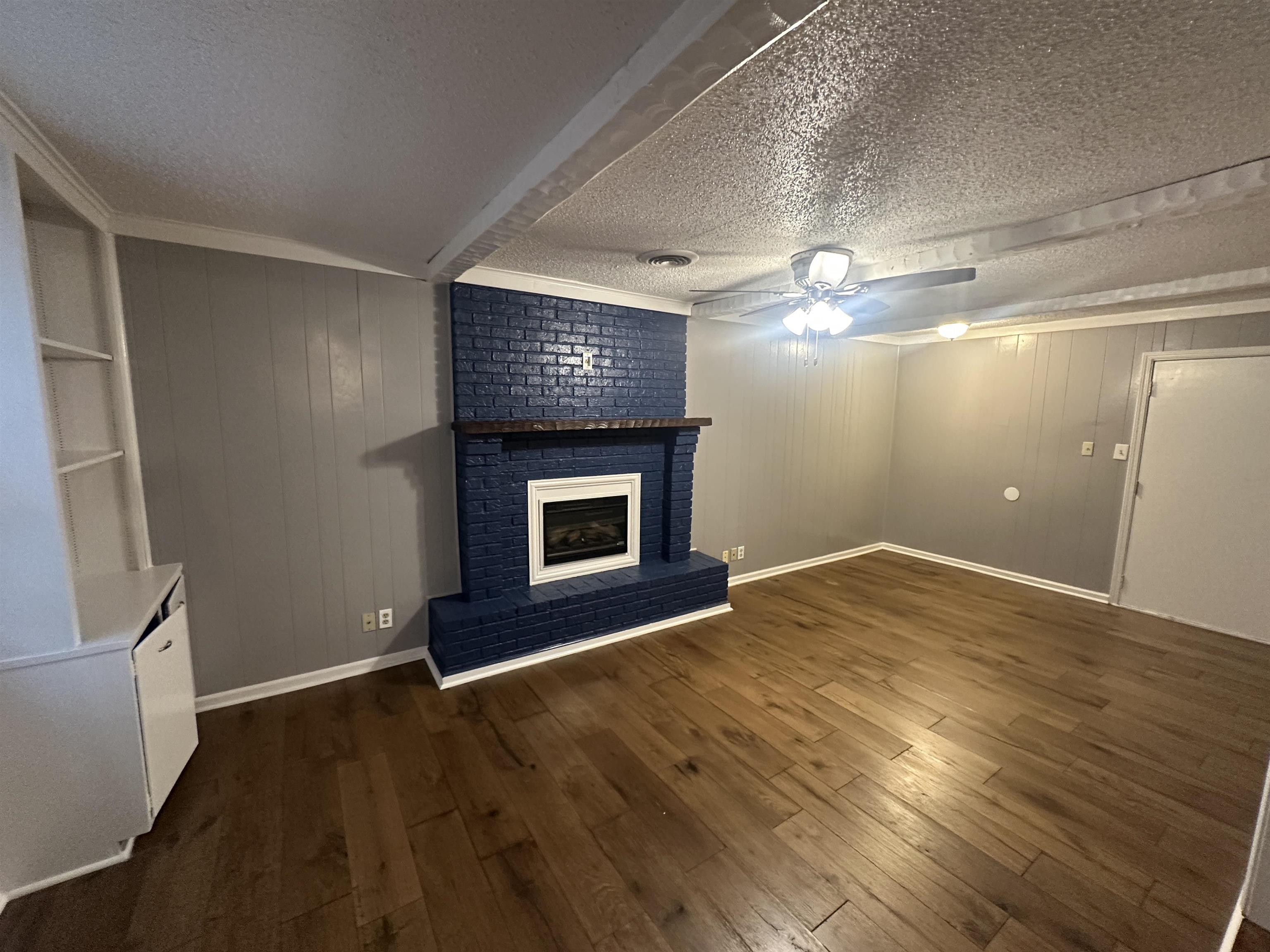 1285 Old Hickory Road Memphis, TN 38116 - Photo 10 of 31 Unfurnished living room featuring a textured ceiling, dark wood-style flooring, a brick fireplace, and a ceiling fan