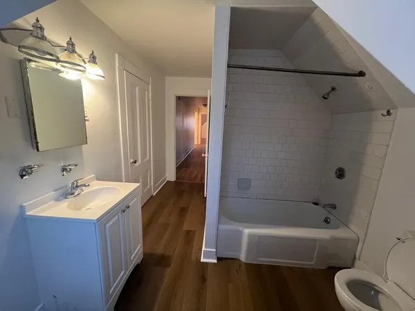 a bathroom with a tub sink toilet and a mirror