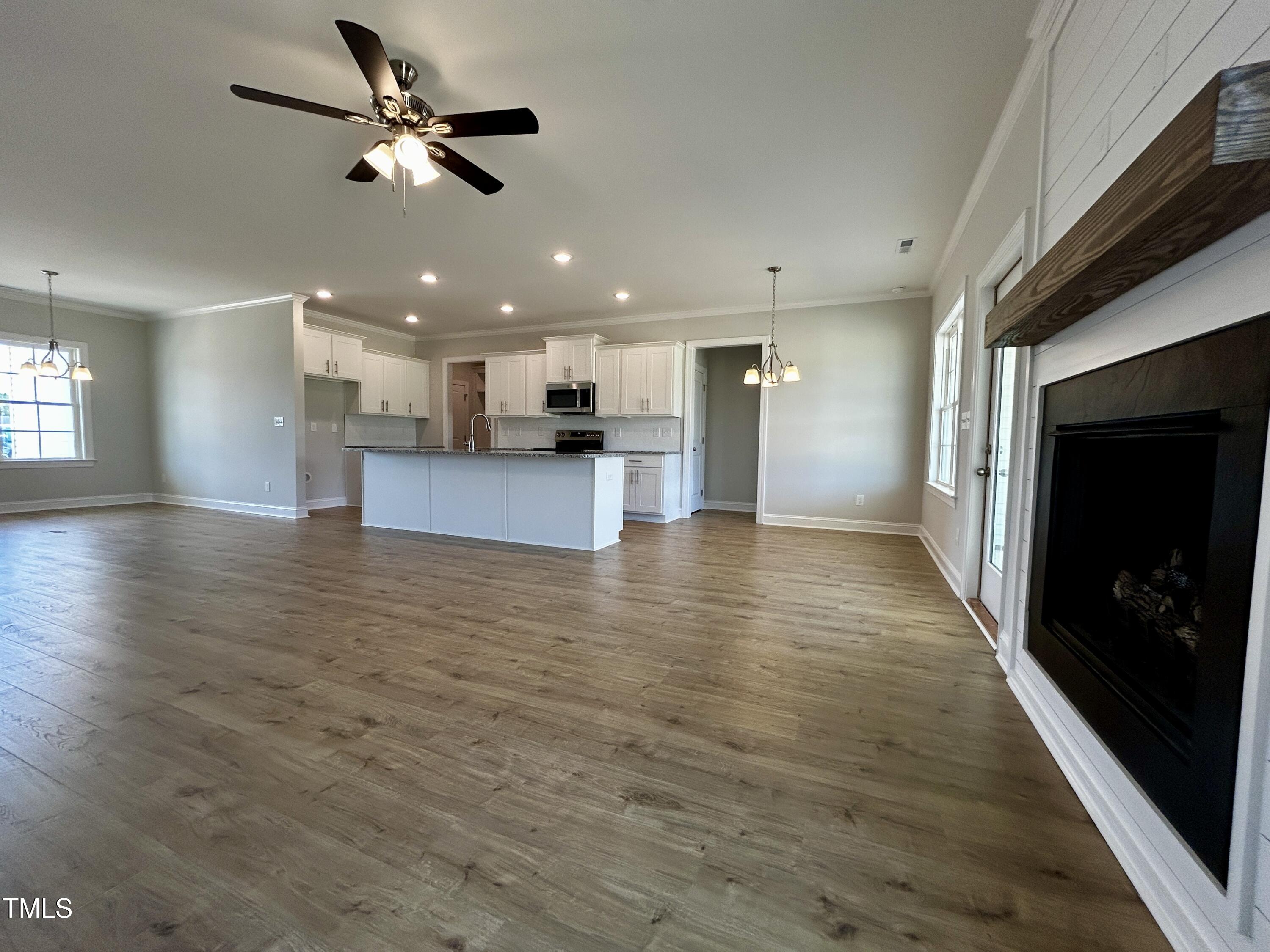 3912 Origin Drive Bailey, NC 27807 - Photo 4 of 20 an empty room with wooden floor a ceiling fan and kitchen view