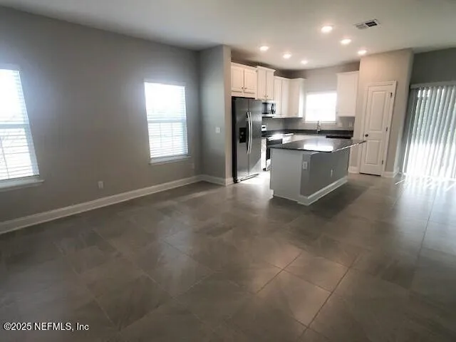 a large kitchen with stainless steel appliances granite countertop a stove a sink a refrigerator and white cabinets with wooden floor