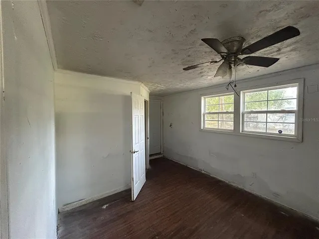 an empty room with wooden floor fan and windows