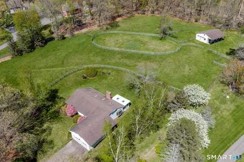 an aerial view of a residential houses with outdoor space and trees all around