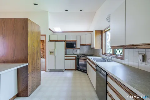a kitchen with stainless steel appliances granite countertop a refrigerator a sink dishwasher stove and oven