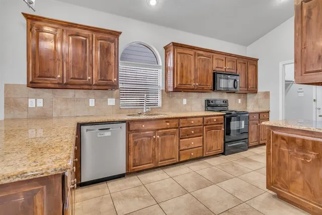 a kitchen with stainless steel appliances granite countertop a stove a sink and a microwave